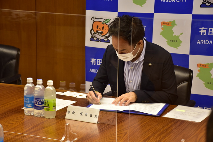 写真：協定書にサインする市長